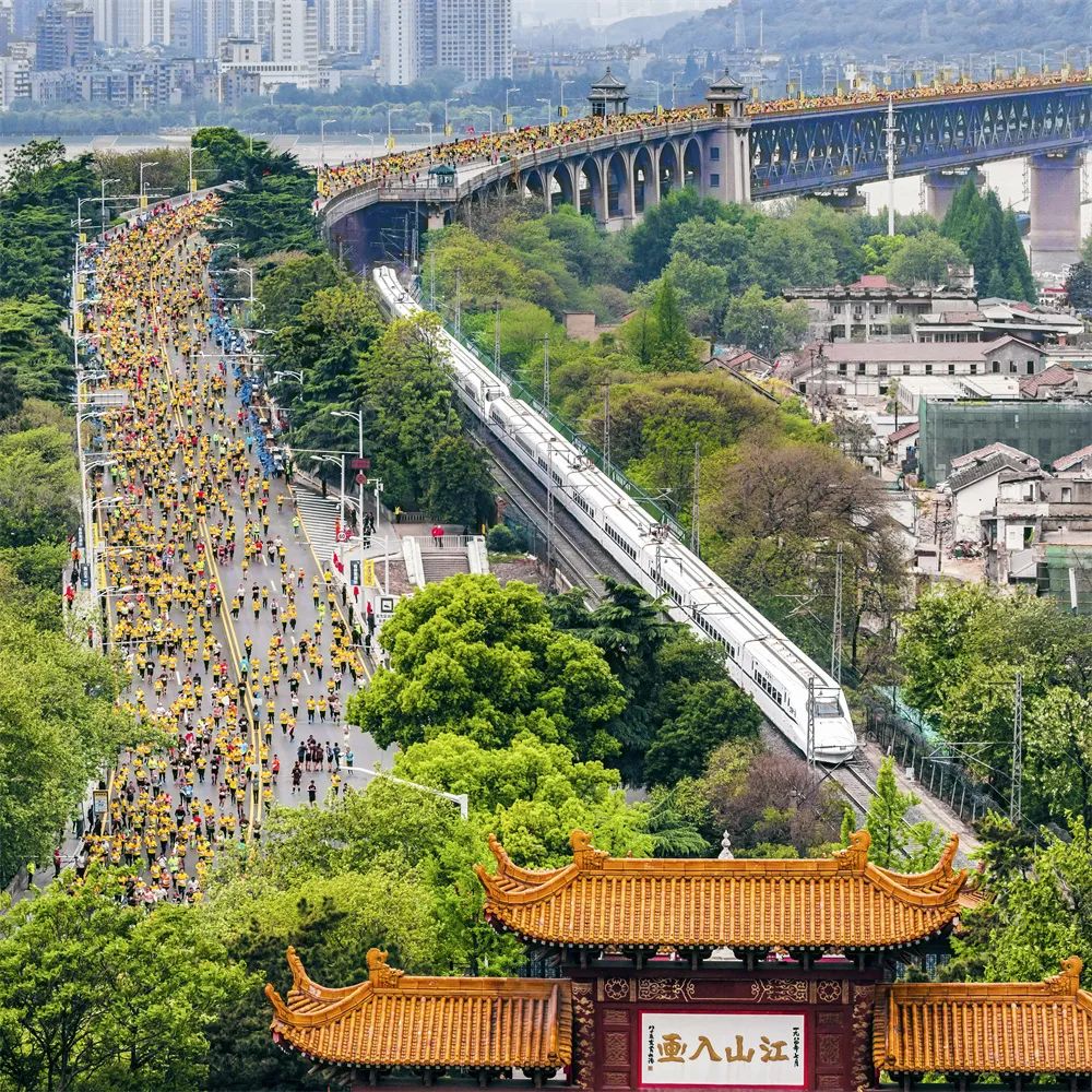 齊頭并進 姜濤 攝2019年4月14日，參加馬拉松比賽的選手們經過武漢長江大橋，與動車同行，與黃鶴樓同框。.jpg