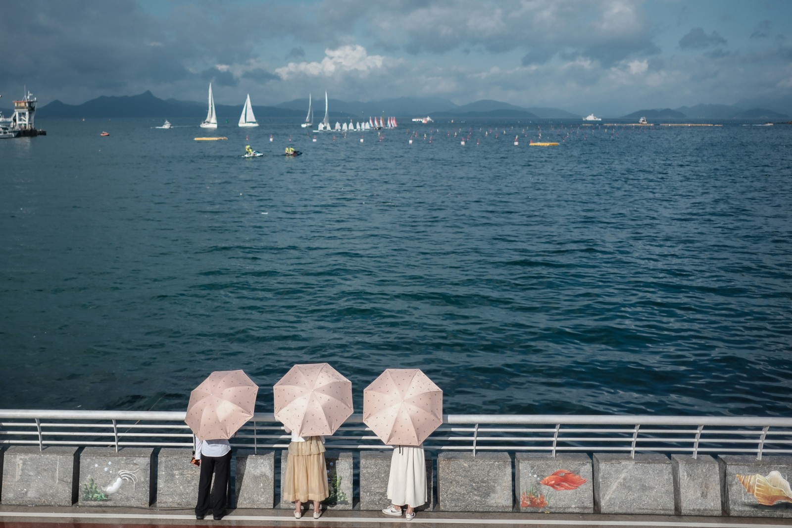 看 海-2023年6月20日，深圳南澳海邊，烈日下，游客打傘看海，遠(yuǎn)處是在為端午舉辦龍舟賽正在進(jìn)行訓(xùn)練的賽手們。-薛云麾.jpg